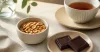 Small bowl of nut spread with dark chocolate squares and measured nuts