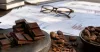 Dark chocolate, cocoa beans and research papers arranged on a neutral desk