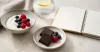 Measured dark chocolate portion with fruit, plain yogurt and a nutrition notebook