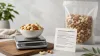 Salted roasted nuts in a measured small bowl beside a nutrition label and kitchen scale