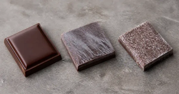 Close view of unbranded chocolate pieces showing smooth, fat-bloomed and sugar-bloomed surfaces Close view of unbranded chocolate pieces showing smooth, fat-bloomed and sugar-bloomed surfaces